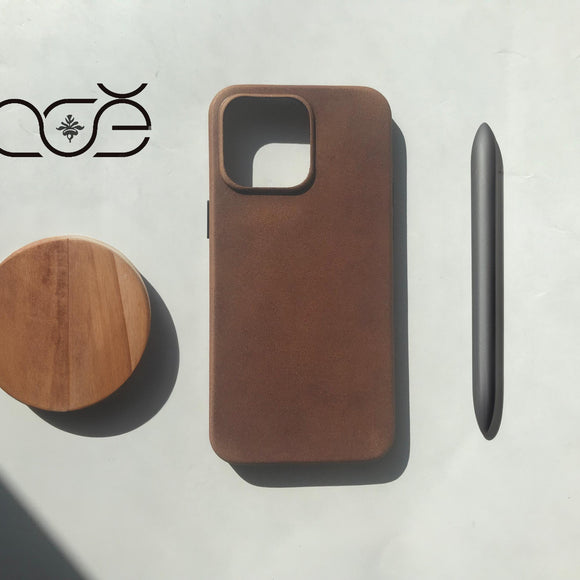 Brown iphone case, wooden coaster, and black pen