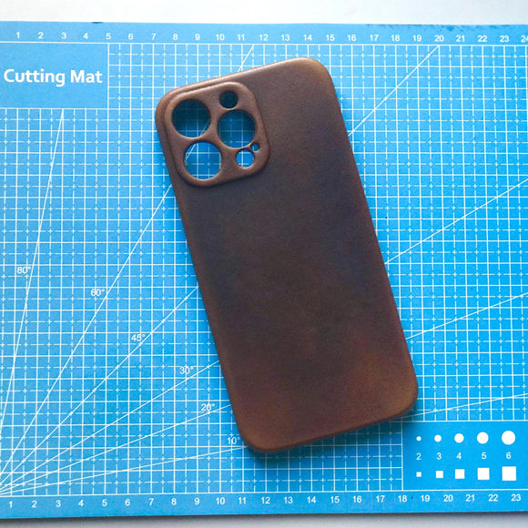 Brown phone case on a blue cutting mat with grid lines