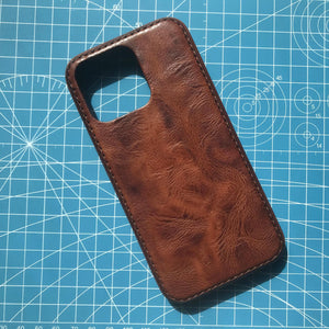 Brown leather phone case on a blue cutting mat with grid lines