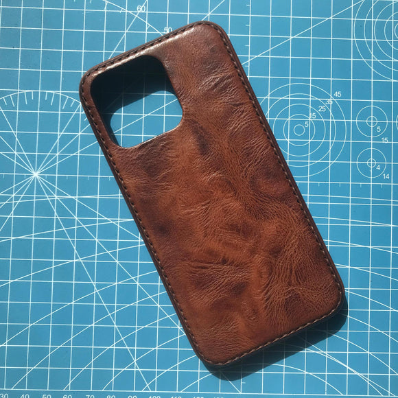 Brown leather phone case on a blue cutting mat with grid lines